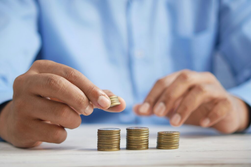 Person stacking coins into small piles, representing how to build an emergency fund through consistent saving