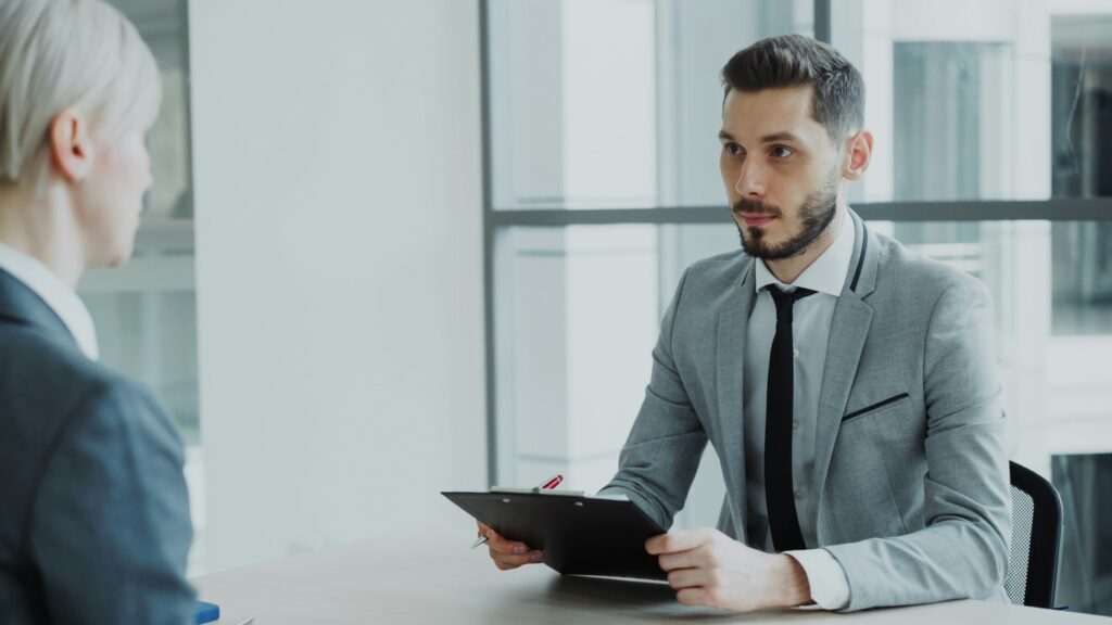 Man in a suit holding a clipboard during a job interview in a modern office