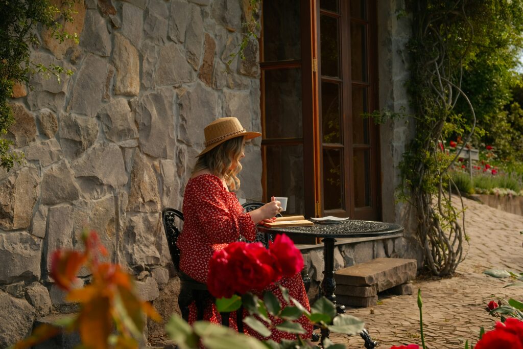 Person enjoying a quiet morning outdoors with coffee and a book, representing financial independence and slow living